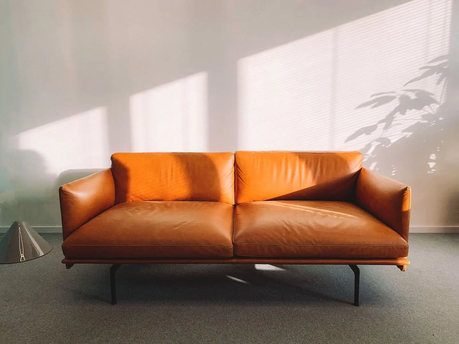 Skórzana sofa w słońcu na tle jasnej ściany